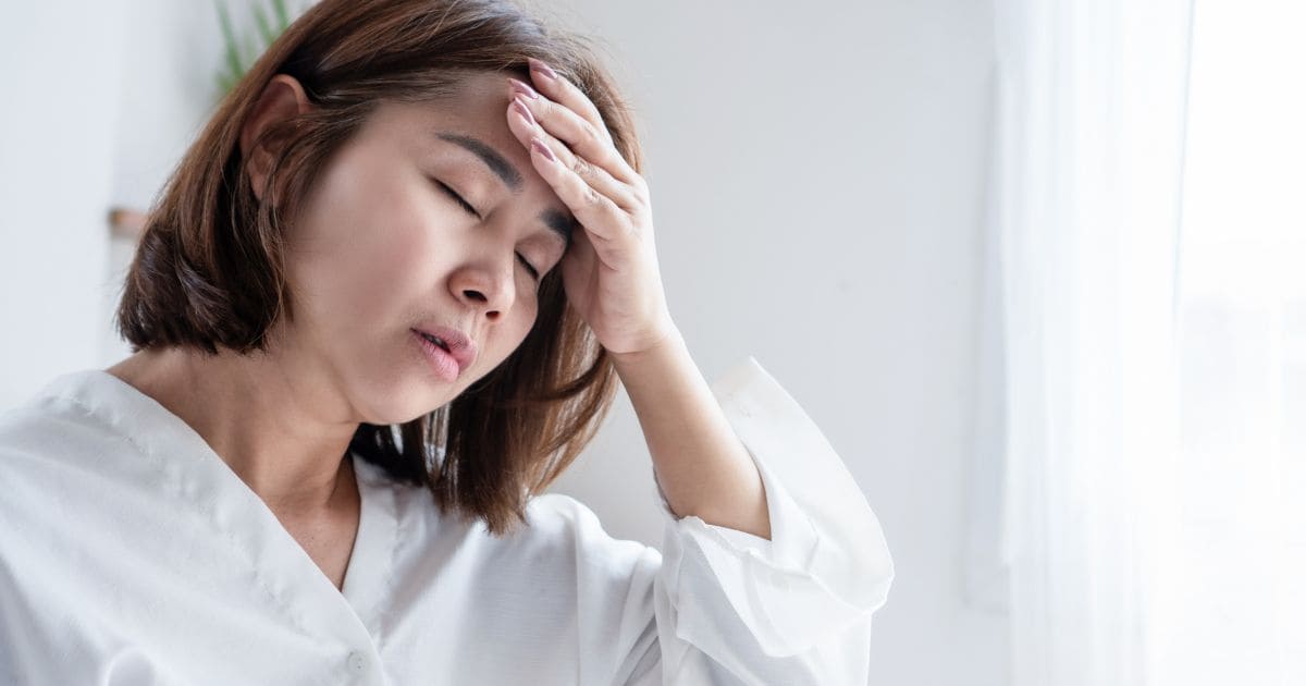 Woman holding her head, illustrating fatigue or brain fog linked to digestive issues