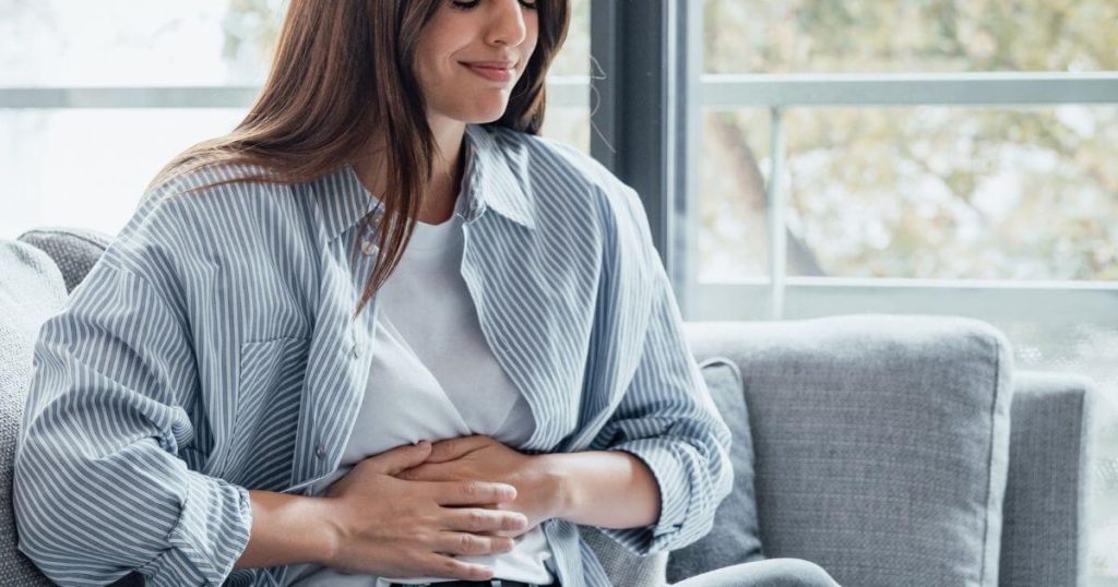 Woman experiencing abdominal discomfort, holding her stomach