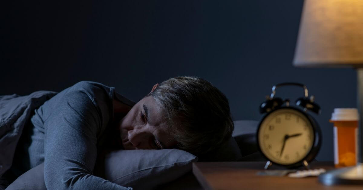 Man lying awake at night, representing sleep disturbances linked to gut health

