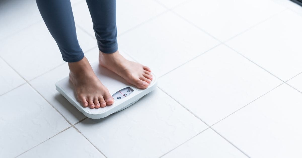 Person on a scale, representing weight changes linked to gut health
