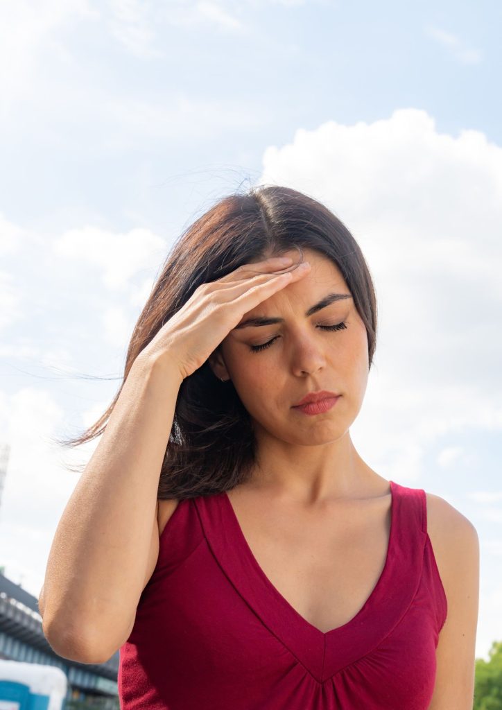 Woman with hand on forehead, distressed with SIBO and dizziness