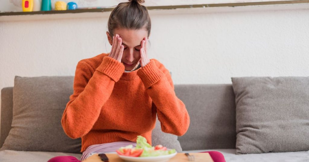 Woman feeling anxious while sitting in front of a meal