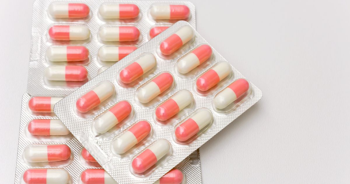 Blister packs of red and white antibiotic capsules used in H2S SIBO treatment.