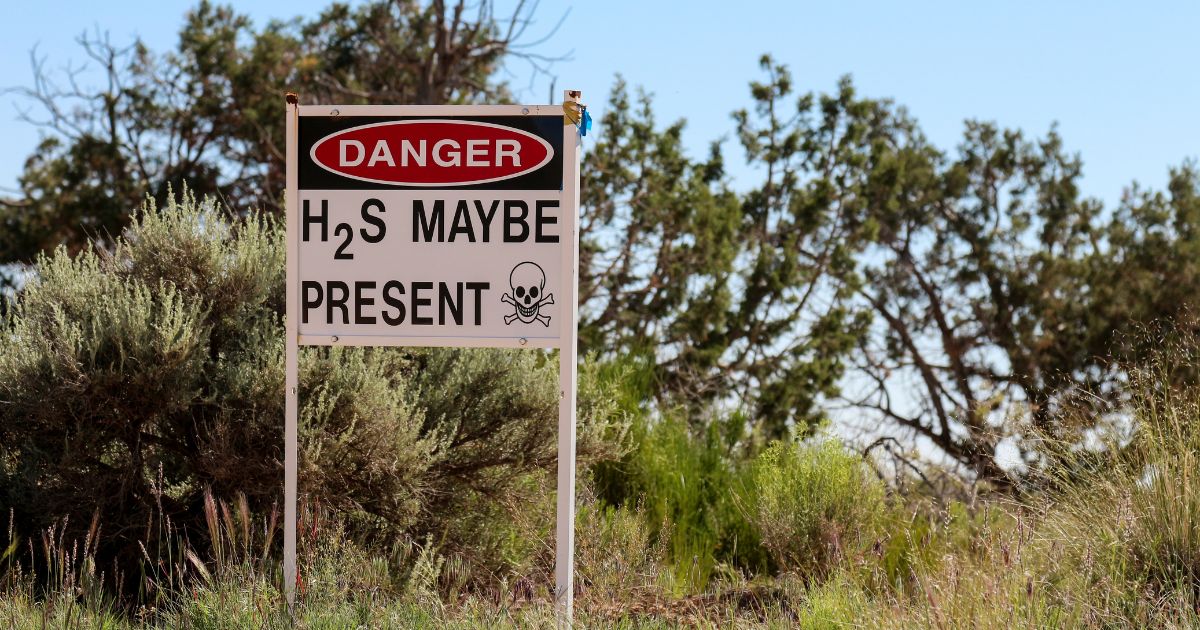 Outdoor warning sign stating hydrogen sulphide may be present.